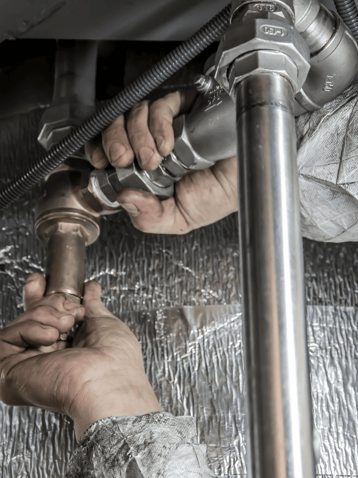 Close-up of hands tightening plumbing pipe fittings.